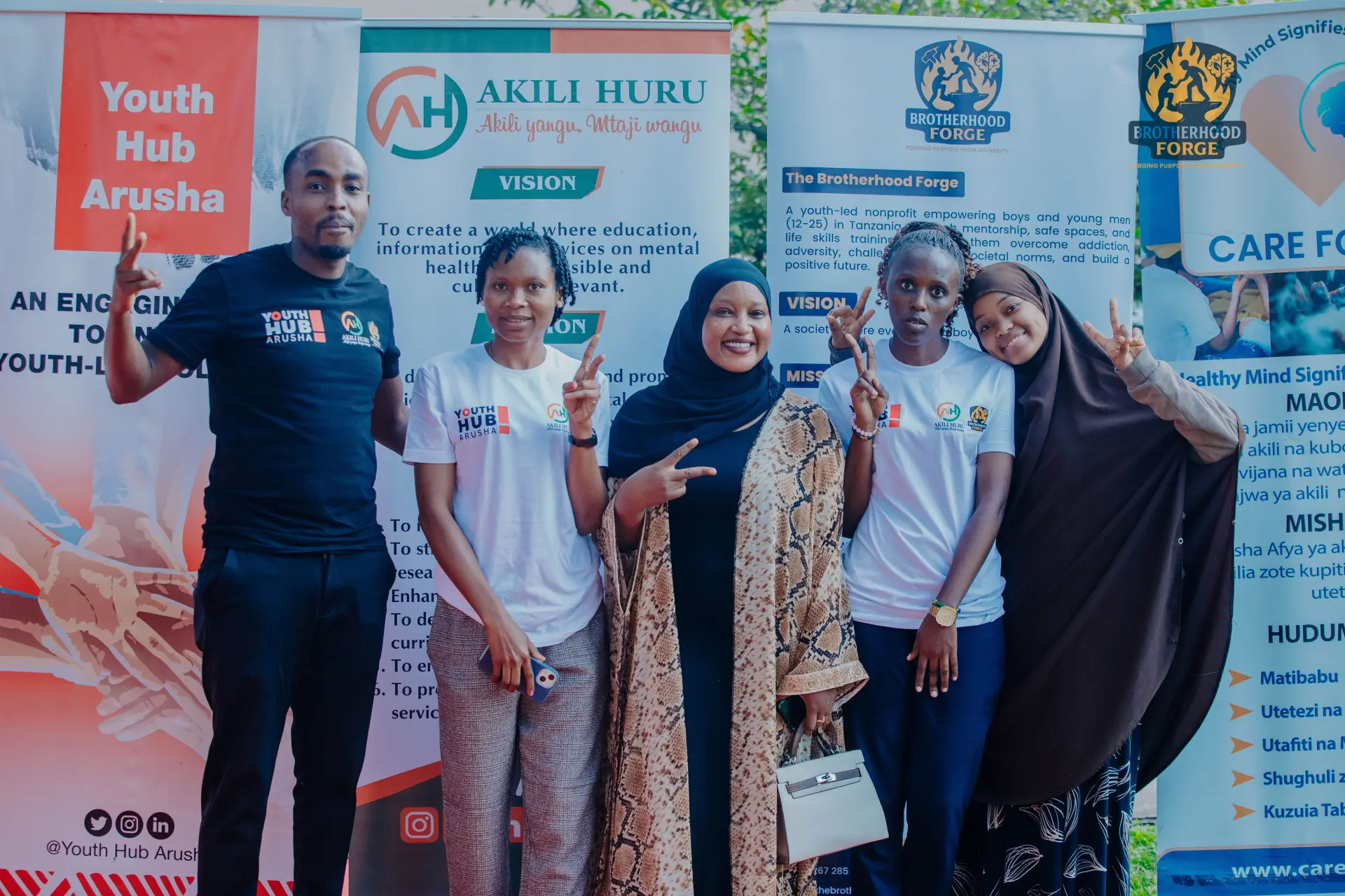 Brotherhood Forge staff, youth, and supporters smiling together in front of community partner banners
